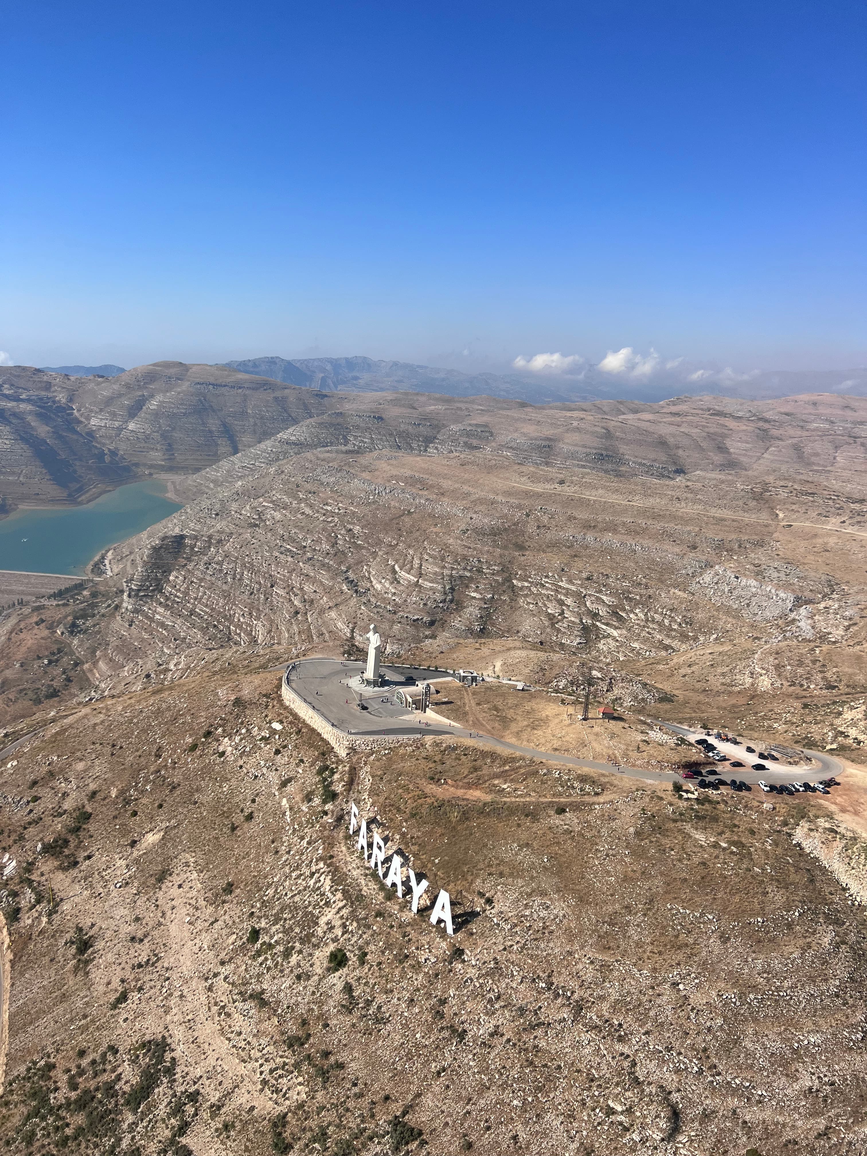 Aerial view of Saint Charbel statue and FARAYA sign above Shabrouh Dam, Lebanon