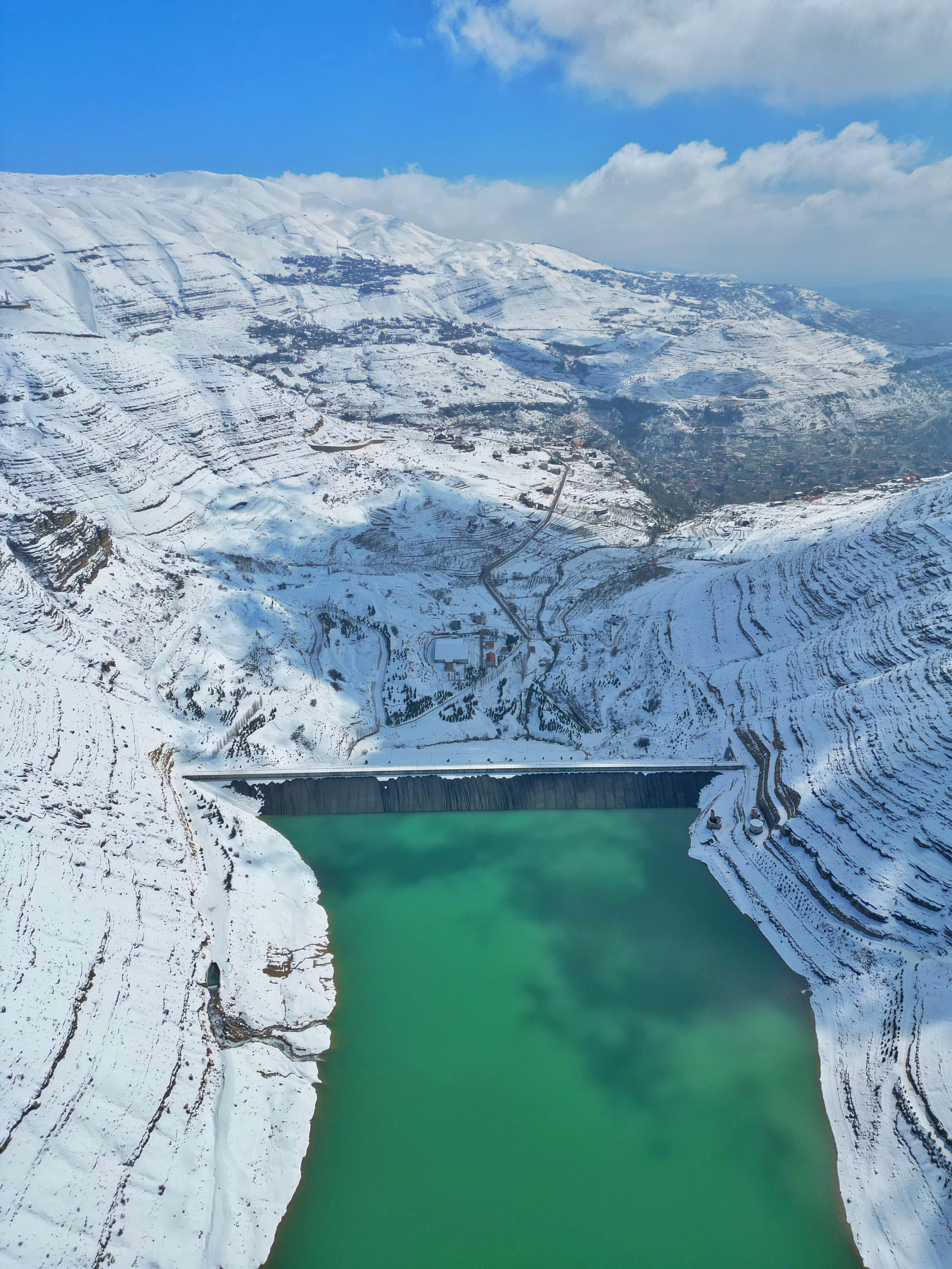 Turquoise Shabrouh Dam surrounded by snowy Faraya mountains