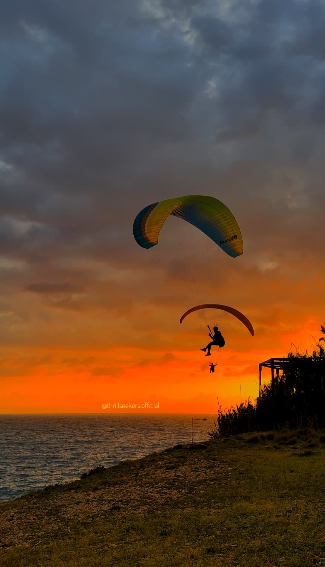 Two paragliders silhouetted at sunset over Lebanese coastal cliffs